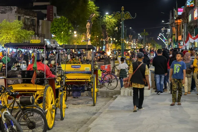 Suasana malam koridor perkotaan Malioboro dan Pasar Kembang Yogyakarta dengan pencahayaan hangat dan aktivitas pejalan kaki